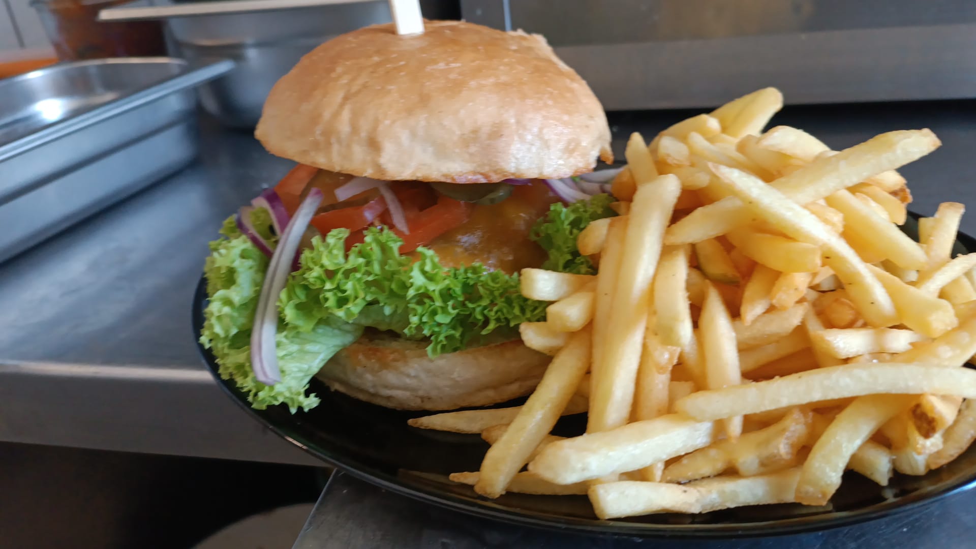 Ein Teller mit einem Hamburger, Salat und Pommes frites; saftig und frisch angerichtet.